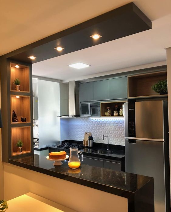 armário de cozinha planejado nas cores preto fosco e balcão com iluminação amarelada.
