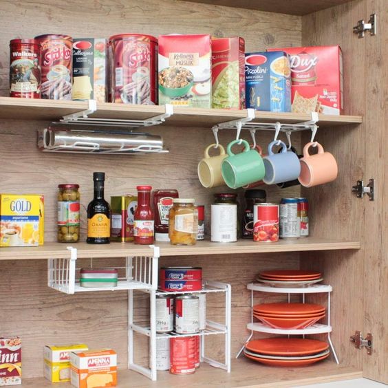Armário de cozinha aberto com suportes para organizar os utensílios e comidas, incluindo ganchos para pendurar xícaras. 