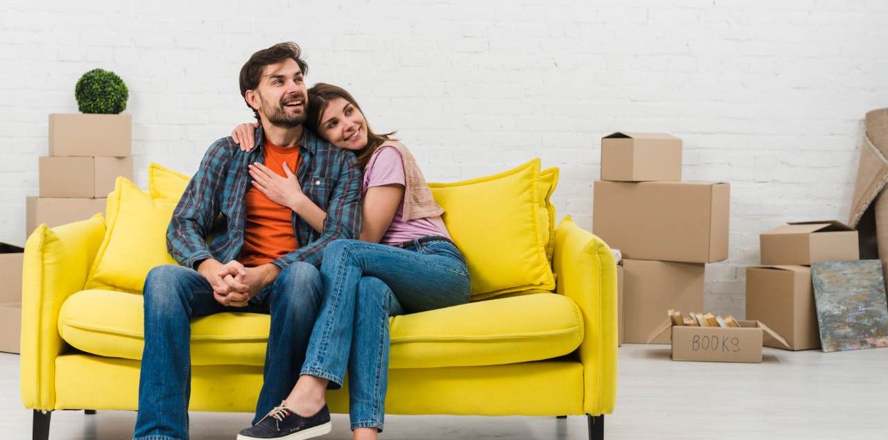Casal em sofá na casa nova