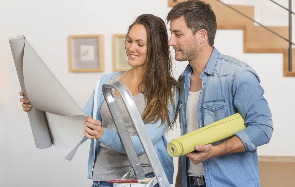 casal hetero branco olhando papel de parede cinza em meio a uma reforma