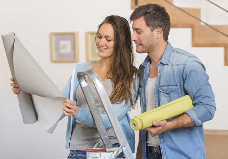 casal hetero branco olhando papel de parede cinza em meio a uma reforma