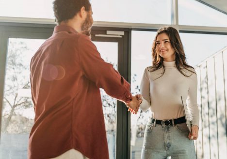 homem corretor apertando a mão de compradora em venda de imóvel