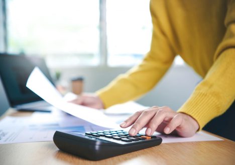 mãos fazendo contas com uma calculadora e papel na mão