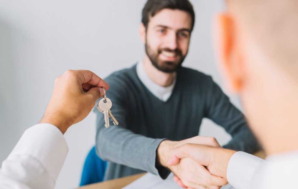 homem dando as mãos para outro com chave na mão em foco