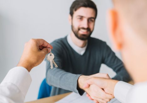 homem dando as mãos para outro com chave na mão em foco